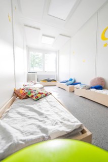 Sleeping room for children with beds and colourful cushions, flooded with light and quiet,