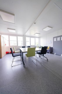 Bright meeting room with various chairs and table in a modern style, transitional daycare centre in