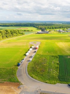 Country road with parked vehicles and extensive fields in a rural setting, ING Park development