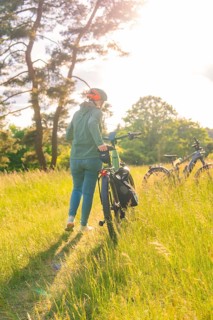 A person pushes a bicycle through high grass in a sunny field, e-bike excursion, Gechingen,