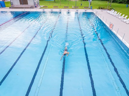 A swimmer moves alone through the lanes of a large swimming pool, Calw outdoor pool, Black Forest,