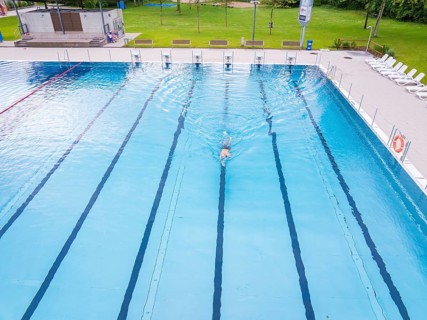 A swimmer swimming his laps in a large, empty swimming pool, Calw outdoor pool, Black Forest,