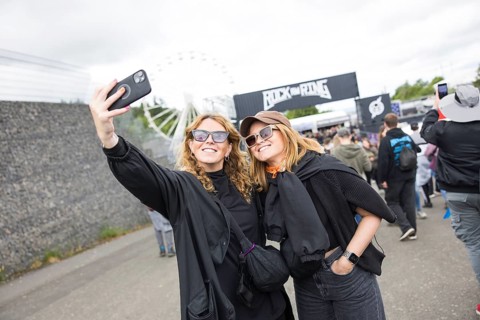 Two festival visitors take a photo of themselves in front of a container with the Rock am Ring logo