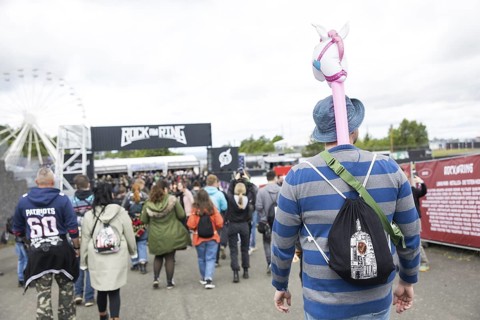 A festival visitor carries an inflatable unicorn in front of a container with the Rock am Ring logo