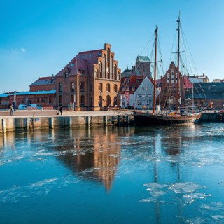 Winter in the Old Harbour with historic sailing ship, ice on the water, brick architecture of