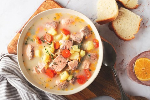 A bowl of soup on a light background, Finnish fish soup, lohikeito soup, creamy fish soup