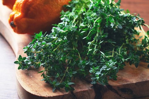 Lemon thyme, on a wooden chopping board, with lemons, close-up