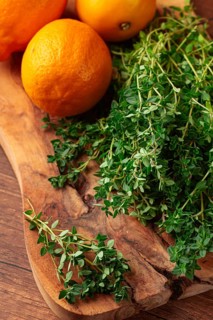 Lemon thyme, on a wooden chopping board, with lemons, close-up