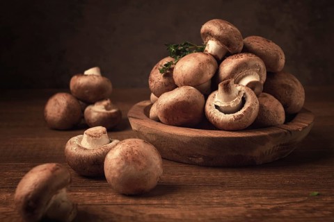 Brown champignons, royal mushrooms, in a wooden bowl, on a wooden table