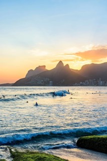 Surfing on Ipanema beach in Rio de Janeiro during sunset with the Two Brothers hill in the