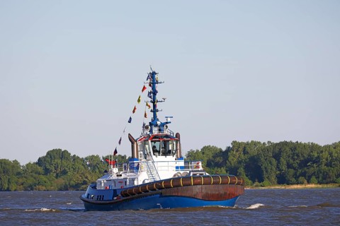 Decorated ship type Fairplay-91 tugboat leaves the port of Hamburg on the Elbe after Hamburg's port