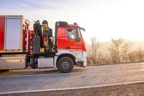 Fire engine on the road towards sunrise, landscape in the background, fire department exercise on
