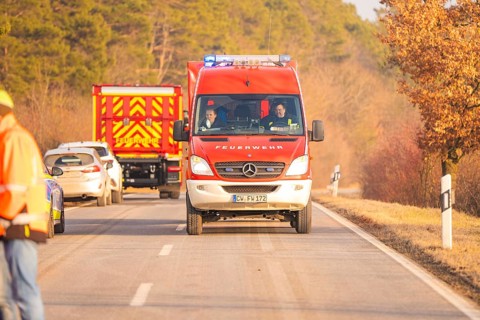 Two fire engines drive on a country road, road markings visible, fire brigade exercise on the
