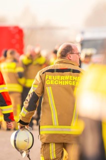 Firefighter with helmet in hand, blurred background activity, fire brigade exercise on the Hermann