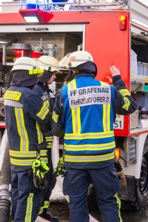 Firefighters are preparing to carry out extinguishing measures on a red vehicle, fire brigade
