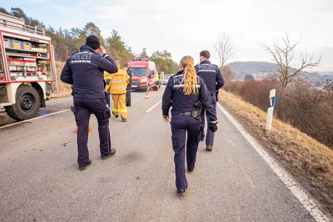 Officials are walking on a street towards an operation. Ambulances and fire engines can be seen,