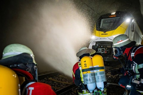 Firefighters spray a train in a tunnel with water. Respirators are used, fire department exercise