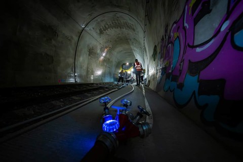 People work in the dark tunnel. Technical equipment and colorful graffiti on the walls, fire