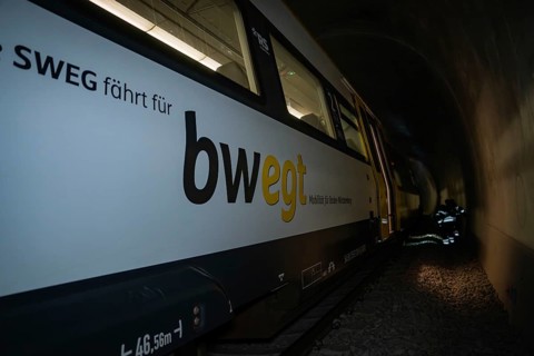 Train in a tunnel with lettering on the side in dark surroundings, fire department exercise on the