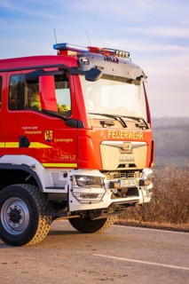 Red fire engine on a street in sunshine, fire brigade exercise on the Hermann Hesse railway,