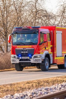 Red fire truck is driving on a country road. Barren winter landscape in the background, fire