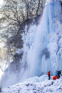 Spectators climb on the Urach waterfall full of bizarre ice formations, frozen at low winter