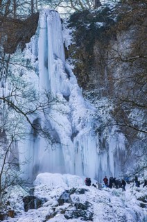 Spectators marvel at the Urach waterfall full of bizarre ice formations, frozen at low winter