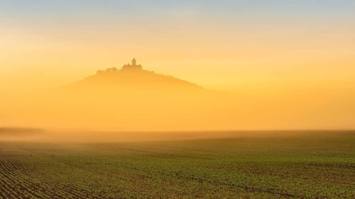 The silhouette of Wachsenburg Castle rises out of the fog at sunrise, Castle of the Three Gleichen