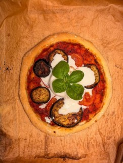 Delicious ready-made homemade pizza with eggplant and burrata on baking paper, food photography,