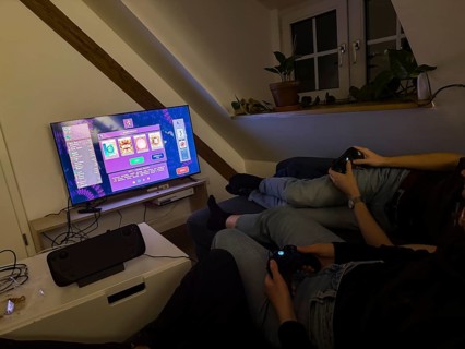 Friends sitting on the couch playing a video game on a TV with Steam Deck, video game Vampire