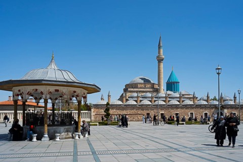 Mosque with minaret and domes under clear sky, traditional atmosphere with people in the