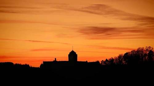 Silhouette of a castle at sunset, warm tones above the horizon, view of Rosenberg Fortress,