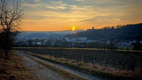Sunset behind a small town, warm light over hills and a country road, view of Rosenberg Fortress,