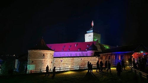 Illuminated castle at night with visitors and colorful lighting, Kronach glows, Frankenwald nature