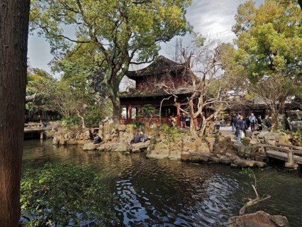 Peaceful garden with pond surrounded by trees and traditional construction, Yuyuan Garden,