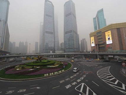 City scene with roundabout and skyscrapers in fog under grey sky, Pudong, Shanghai, China