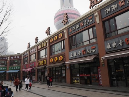Commercial street with people and view of the TV tower on a cloudy day, Pudong, Shanghai, China