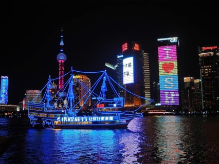 Illuminated skyline and river with an illuminated ship at night, Shanghai, China