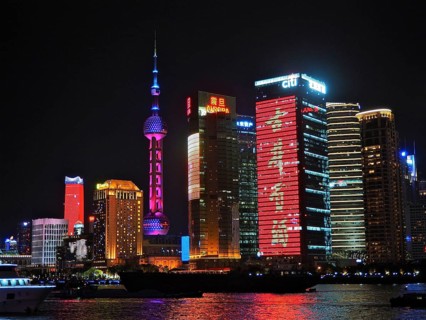 Illuminated skyscrapers and neon signs at night on a riverbank, Shanghai, China