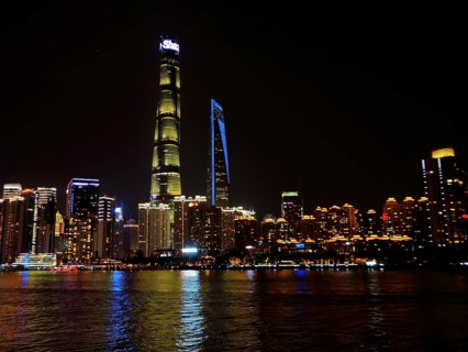 Illuminated city on riverbank at night with clear view of skyscrapers, Shanghai, China