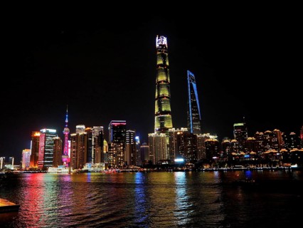 Impressive skyline of high-rise buildings, illuminated at night, stretching behind a river,