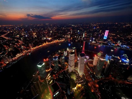 Illuminated city at dusk with view of river and skyscrapers, Shanghai, China