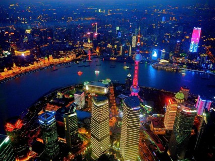Glowing city view at night with illuminated skyscrapers along a river, Shanghai, China
