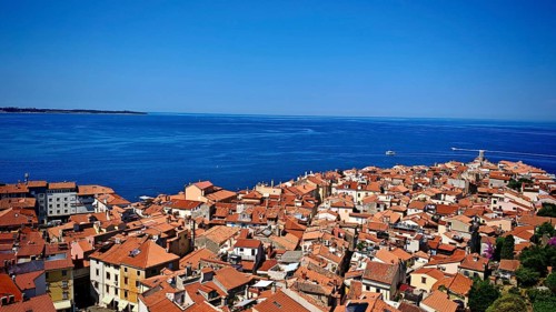 Panoramic view of a coastal town with red roofs and blue sea in the background, Piran, Slovenia