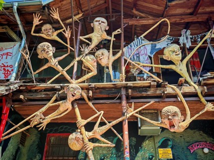 Surreal wooden creatures humorously hang down from a balcony of a building, Ljubljana, Slovenia