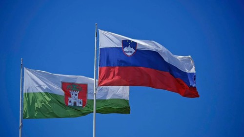 Two national flags flutter side by side against a clear blue sky, Ljubljana, Slovenia