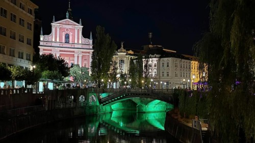 River with illuminated bridge and historic buildings in an atmospheric night view, Ljubljana,