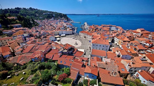 Panoramic view of a coastal town with a main square and red roofs on a clear blue day, Piran,