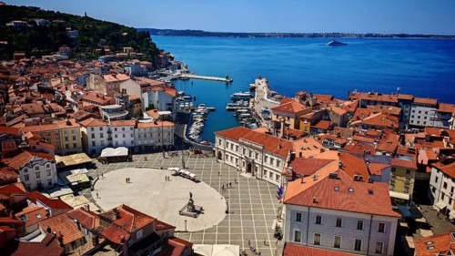 Aerial view of a coastal town with red roofs, a harbor and a main square on the blue sea, Piran,