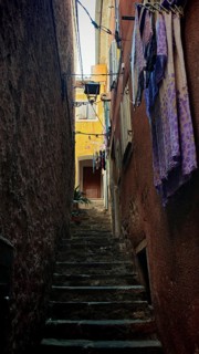 A narrow stone staircase in an old alley with suspended laundry and shade, Piran, Slovenia